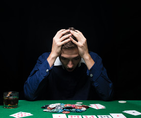 Man is playing poker. Emotional fail in game, game over for card player, man very angry with foolish choices, loosing all the chips on bank. Concept of victory and loosing