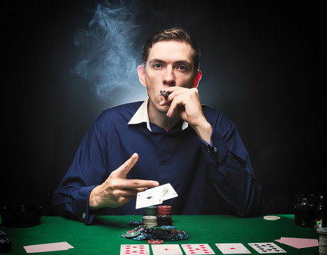 Man is playing poker. with a cigar and a whiskey, a man throws two cards on the table, winning all the chips on the table with thick cigarette smoke. The concept of victory