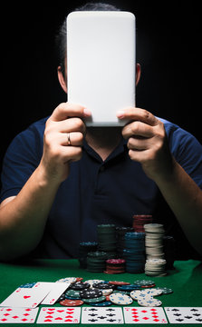 Man is playing poker with tablet online. Emotional  card player win in game, man very happy with making right choices, winning all the chips on bank. Concept of victory and internet online game