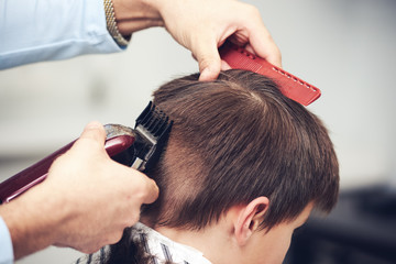 European boy  getting haircut in barbershop.
