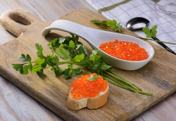 Sandwich with red caviar on a wooden cutting board