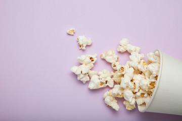 Spilled out of a paper cup, popcorn on a pink background