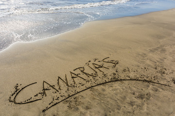Beach of a Canary Island with the word Canaries written in the sand