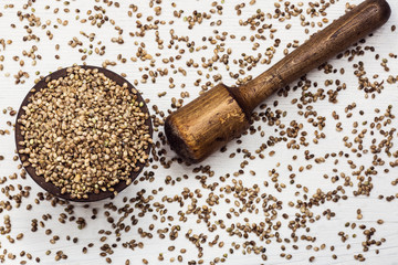 Hemp seeds in an old wooden mortar on a white background.