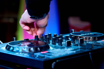 Hands of the DJ behind the control panel.