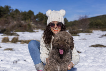 portrait of a young beautiful woman in the snow with her cute dog. Sunny weather. Wearing warm clothes. Lifestyle