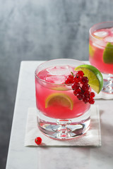 Red Currant Caipirinha or Daiquiri Cocktails with Ice and Lime Wedges on Marble Counter