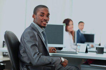 Portrait of a happy African American entrepreneur displaying computer laptop in office.