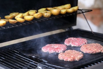 Burgers on grill with potatoes