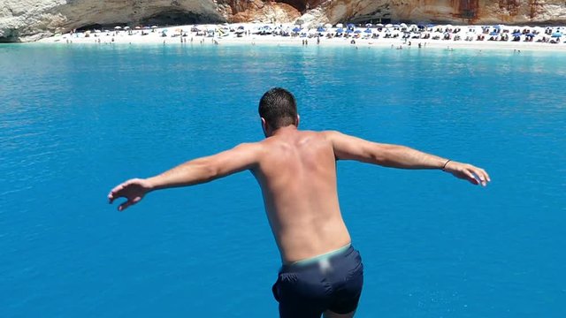 Young man jumping from cruse ship into the sea, having fun and enjoying the freedom of his summer holiday, slow motion