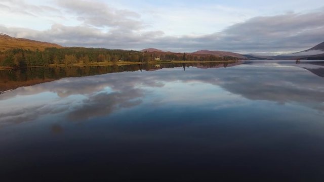 aerial footage of flying over a calm mirrorlike scottish loch in the remote highlands of scotland at loch tulla