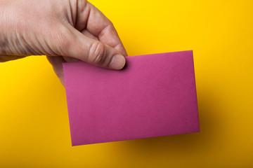 Hand holding a blank flyer, A6 flyer, postcard, invitation mock-up on a yellow background.