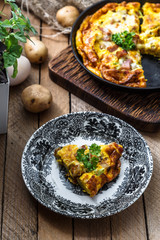 A piece of french baked omelette Savoyarde with ham, cheese, potato and leek on a plate, rustic style, top view
