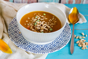 
Pumpkin, carrot and pepper soup. Blue wooden background. Orange tulip.