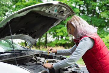 Girl checks the oil in the car's engine
