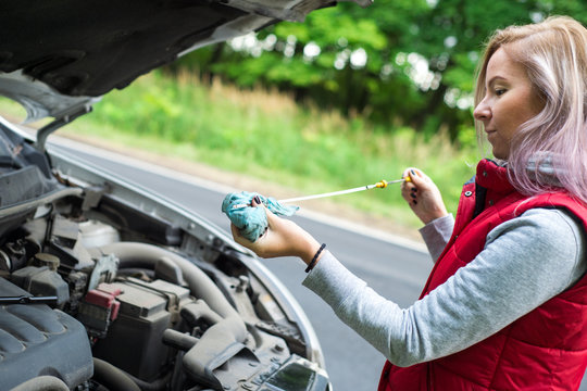 Girl checks the oil in the car's engine