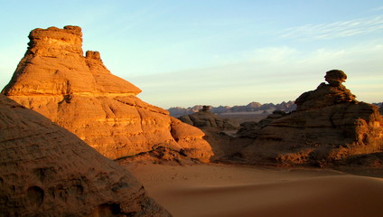 Sandsteinberg strahlt sonnig in der Wüste zwischen Sand und Bergen im Akakusgebirge