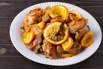 Sweet and sour chicken wings with oranges, served with sesame on white plate
