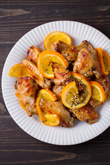 Sweet and sour chicken wings with oranges, served with sesame on white plate