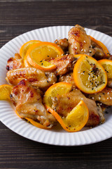Sweet and sour chicken wings with oranges, served with sesame on white plate