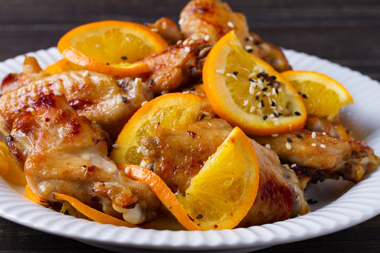 Sweet and sour chicken wings with oranges, served with sesame on white plate