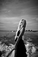 blonde in black long dress floating on a yacht