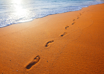 beach, wave and footprints at sunset time