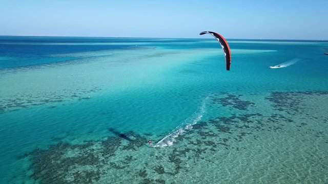 Aerial view young man kite surfing in tropical blue ocean