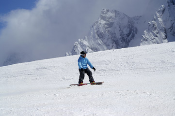 Snowboarder downhill on snowy ski slope in high mountain