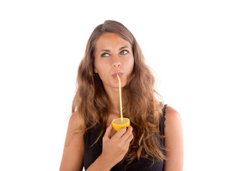 Beautiful girl drinking some natural juice from a real lemon; health and lifestyle concepts, customizable background with copy space