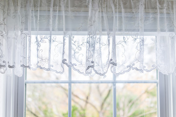 Closeup of small short lace white window curtains blinds in bright room interior indoors with pattern design decoration