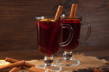 Red mulled wine on burlap on a wooden table with various spices