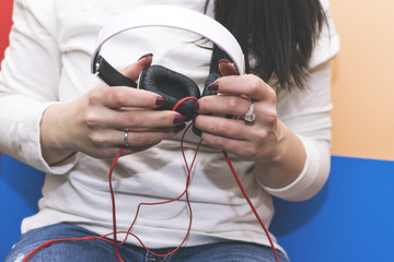 The girl holding a large white headphones.