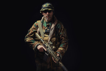 soldier of the American special forces in Afghanistan poses with a rifle on a black background