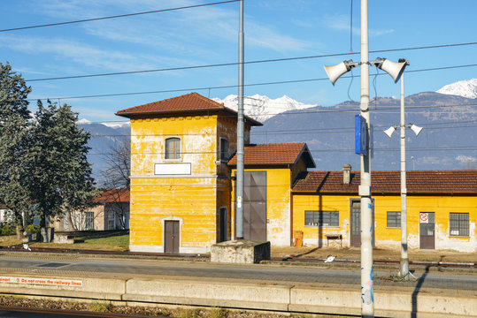 Fototapeta View from outside window of train at small train station and majestic Italian Alps in the background