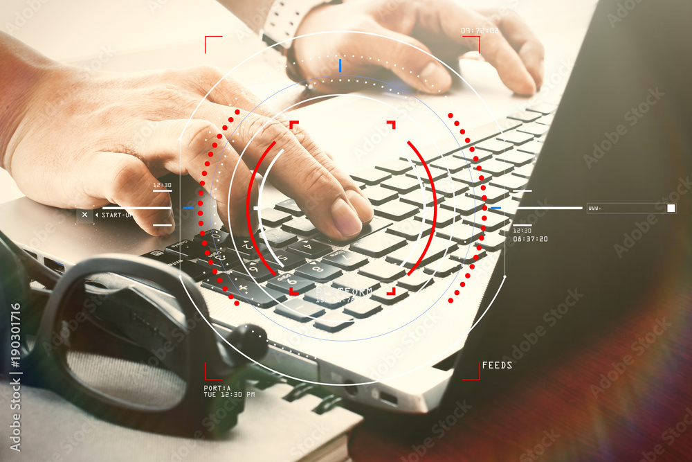 Poster designer hand working with digital tablet and laptop and notebook stack and eye glass on wooden desk in office