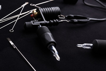 Tattoo machine and tattoo supplies on dark background