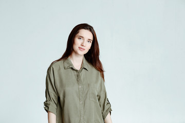 Portrait of a pretty smiling woman brunette with long hair in a green shirt dress posing isolated on a white background