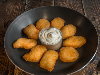 Freshly cooked nuggets in a frying pan with sauce