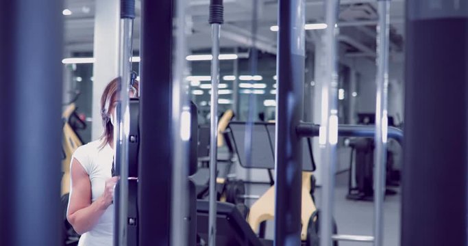 Adult woman doing Exercises for Tricep in fitness gym. Beautiful Woman doing triceps workout. Fitness girl doing triceps cable pushdown exercise in gym