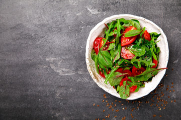  Salad with baby Spinach, arugula and Fresh Cherry Tomatoes Flax seeds and Olive oil.Food or Healthy diet concept.Super Food.Vegetarian.Top View.Copy space for Text. selective focus.