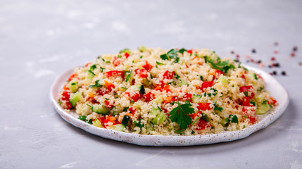 Tabbouleh salad with couscous on the plate.Traditional middle eastern or arab dish.Vegetarian.Parsley,pepper,cucumber,tomato,lemon.Middle eastern meze.Food or Healthy diet concept.Copy space for Text.