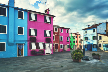 Burano, Venice. Old colorful houses architecture at the square with fountain. Summer 2017, Italy. Cloudy weather, toned