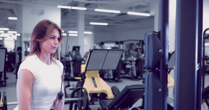 Adult woman doing Exercises for Tricep in fitness gym. Beautiful Woman doing triceps workout. Fitness girl doing triceps cable pushdown exercise in gym