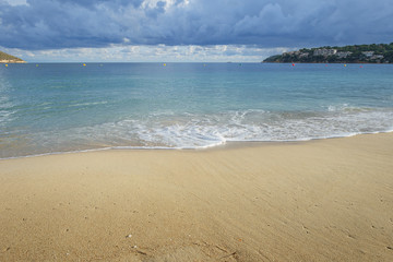 fragment of sandy beach with moveable sea wave close up