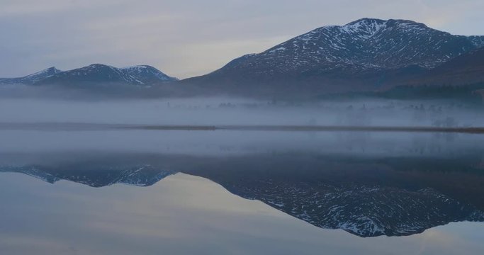 fog rolling in towards the mountains behind loch tulla in the highlands of scotland