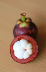 Purple mangosteen or Garcinia mangostana, known simply as mangosteen. Wood background.