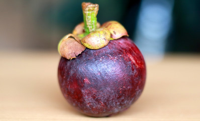 Purple mangosteen or Garcinia mangostana, known simply as mangosteen. Wood background.