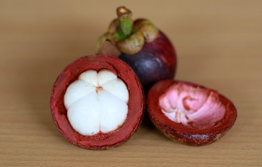 Purple mangosteen or Garcinia mangostana, known simply as mangosteen. Wood background.