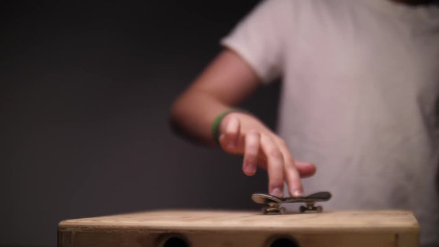KID PLAYING WITH FINGER SKATEBOARD, IN SLOW MOTION